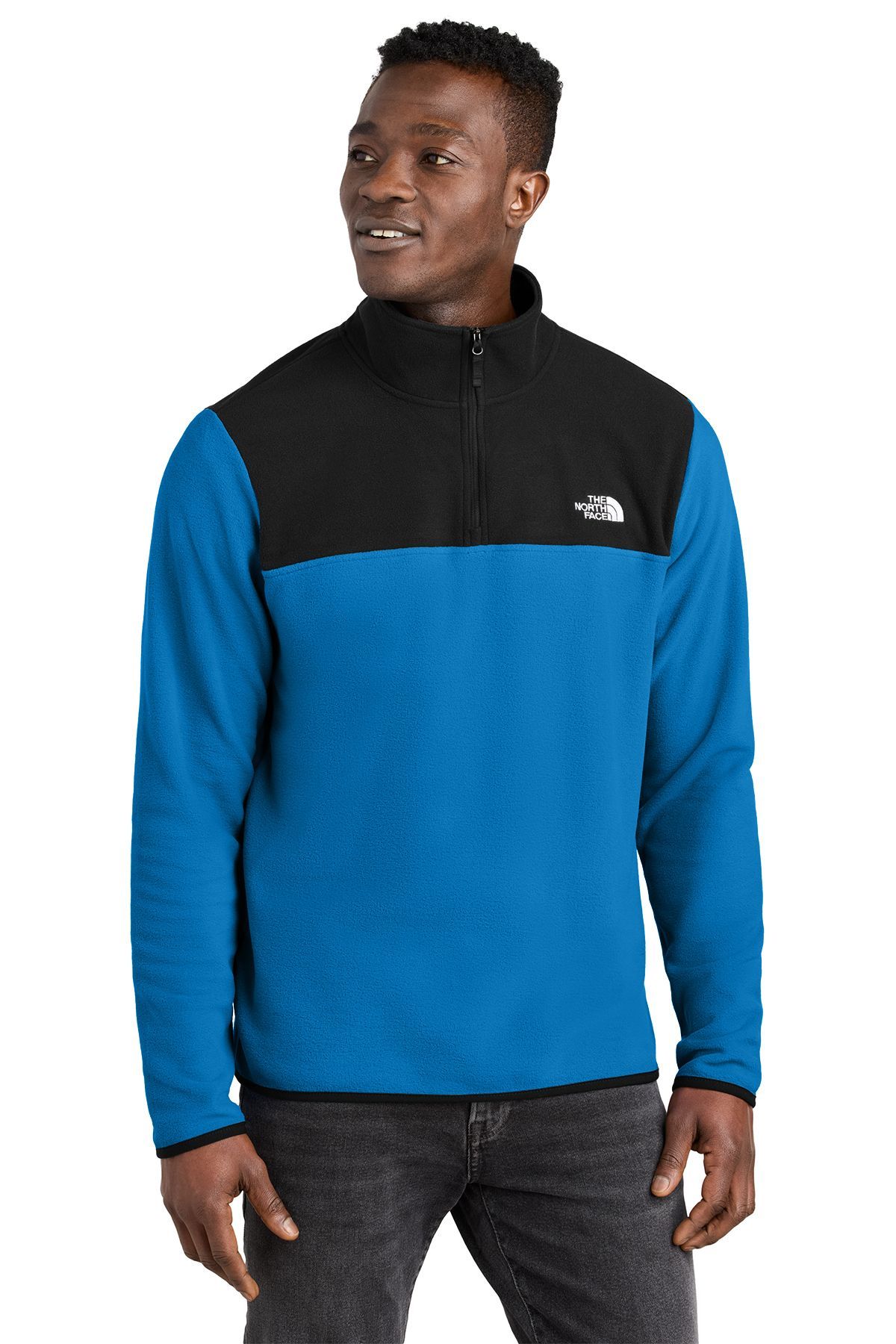 Man in blue and black North Face quarter zip fleece pullover, half-zipped, smiling.