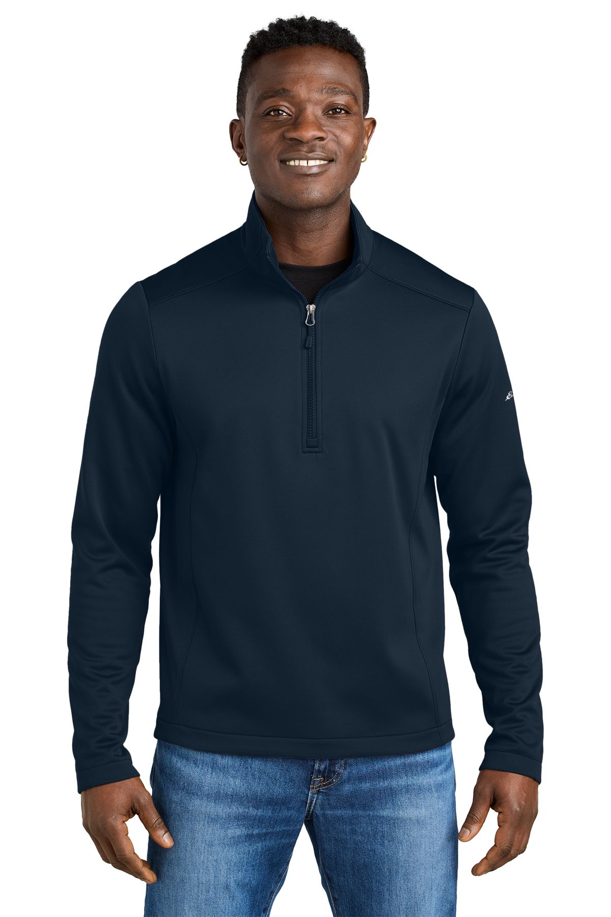 Man in navy blue quarter-zip top and jeans, smiling.
