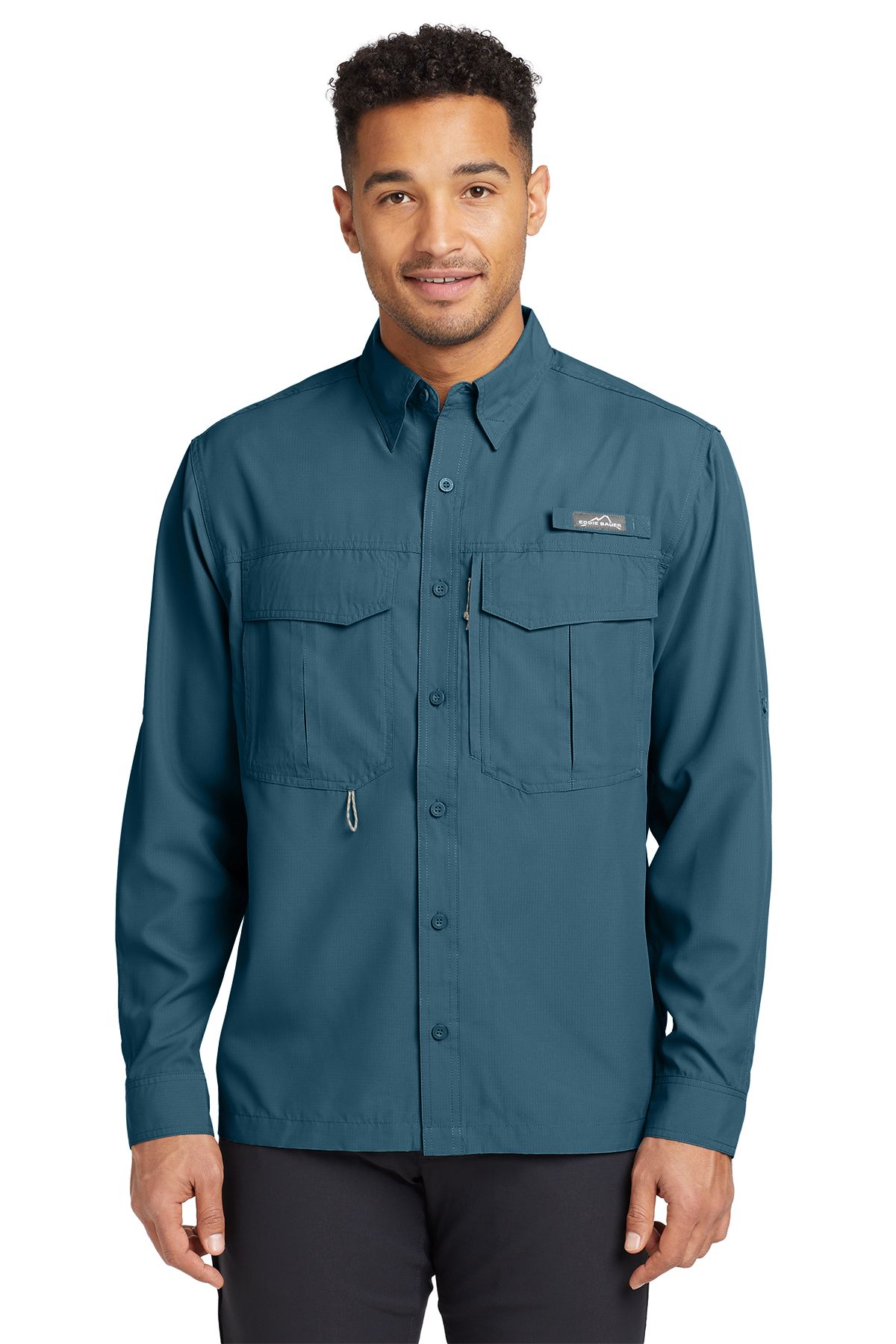 Man wearing a teal button-up shirt with pockets, standing and smiling.