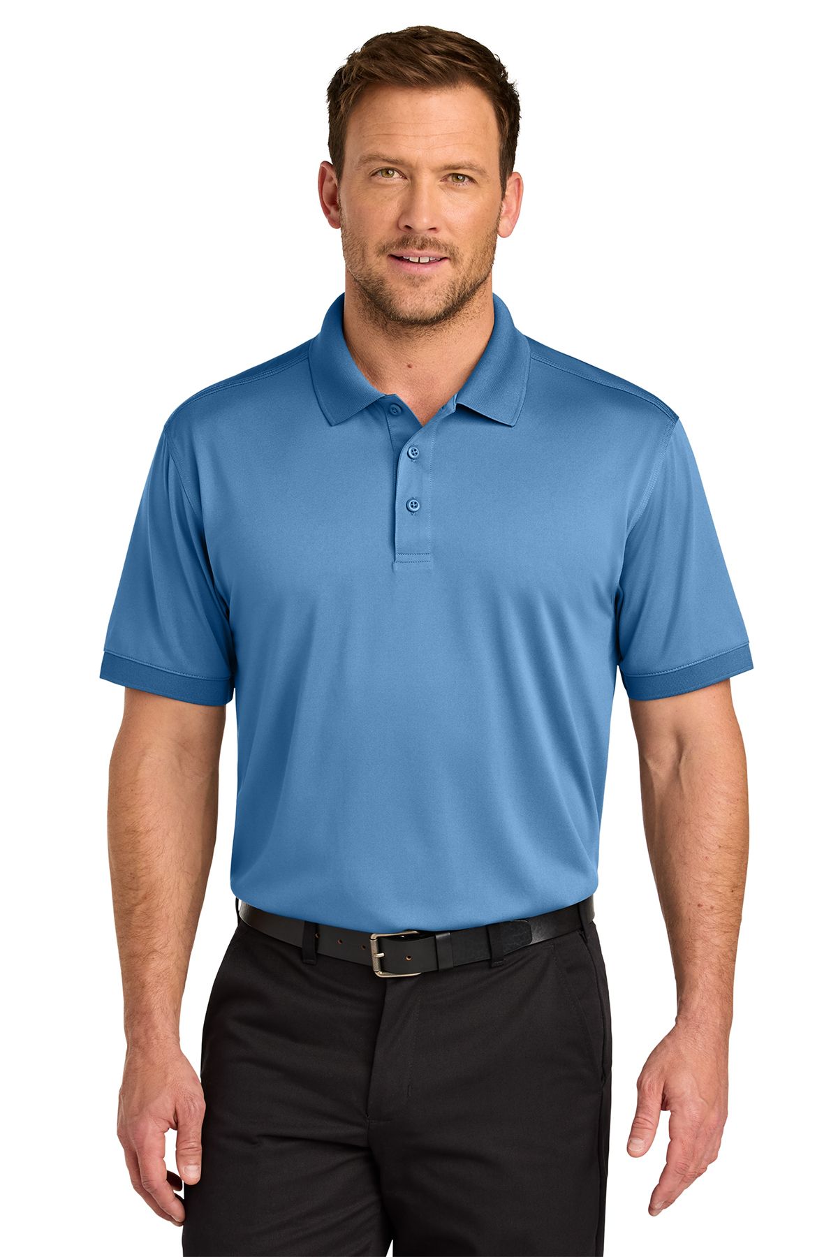 Man wearing a blue polo shirt and black pants, smiling, standing against a white background.