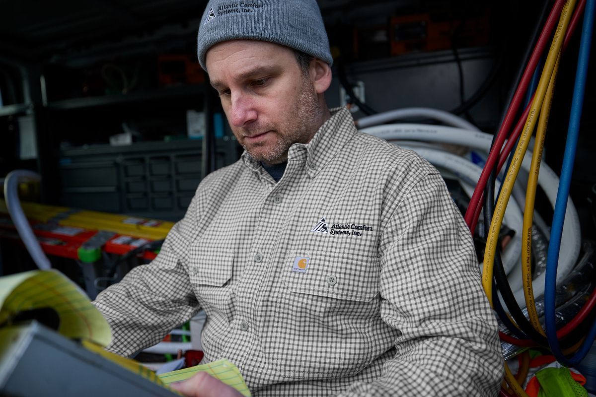 Worker looking at a clipboard earing our Carhartt Plaid Button-Down Work Shirt