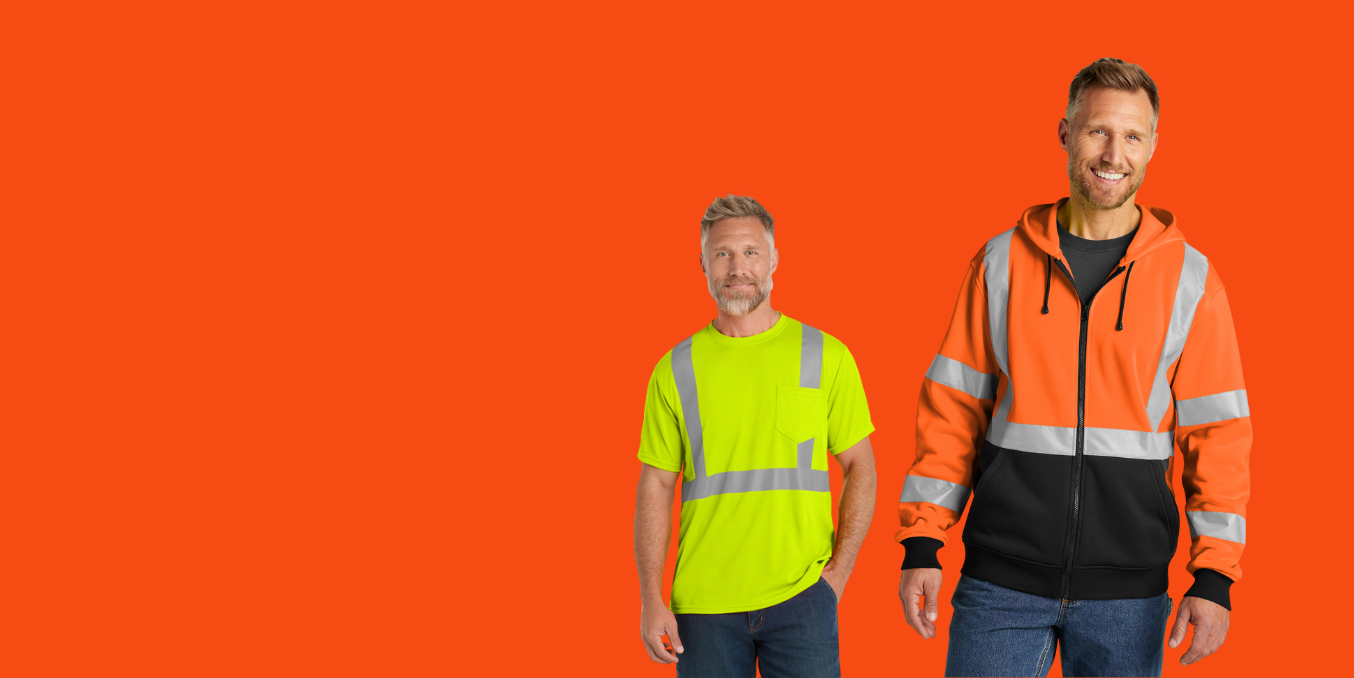 Two men in safety workwear standing against an orange backdrop. One wears a yellow shirt, the other an orange jacket.