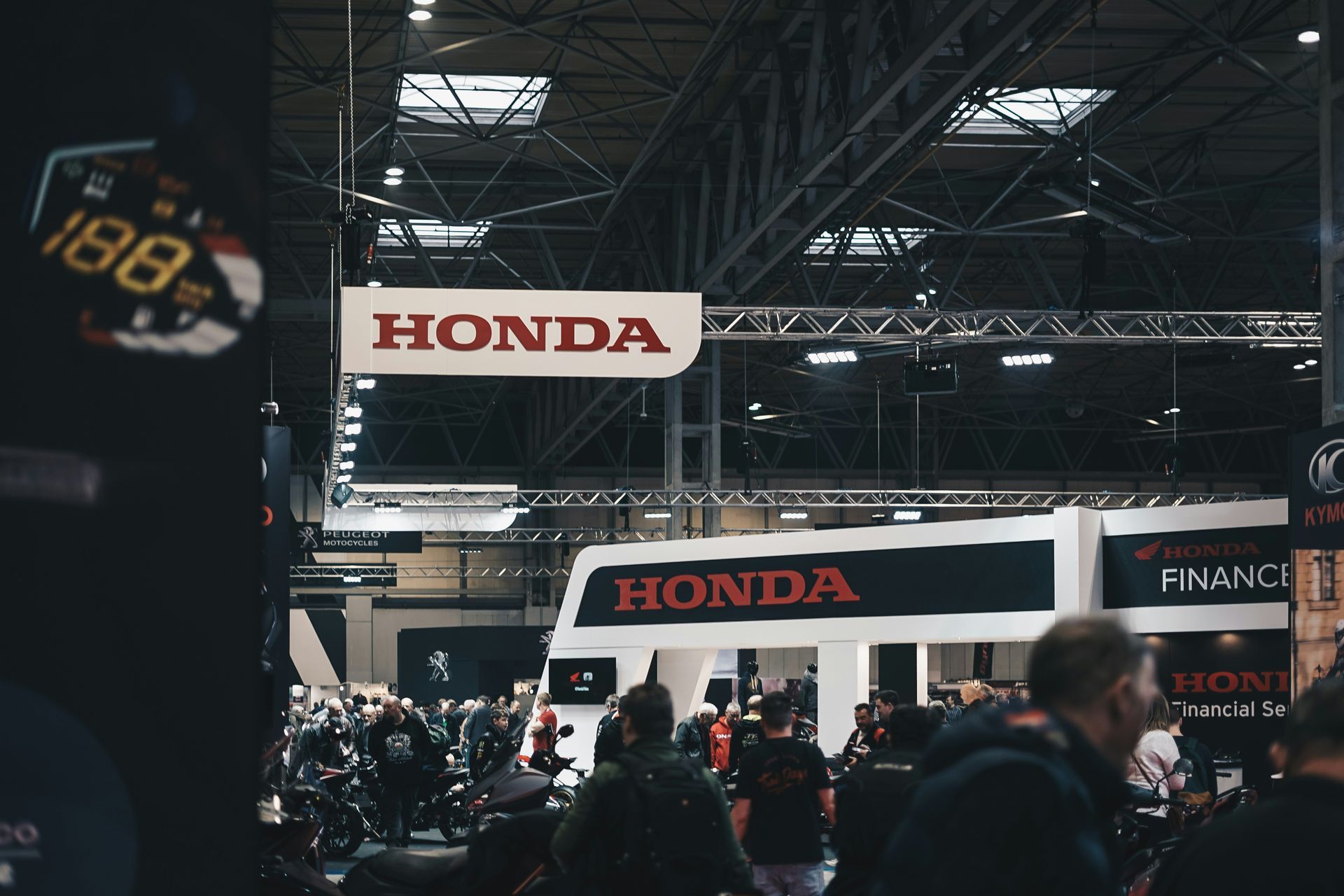 A group of people are standing in front of a honda booth at a motorcycle show.