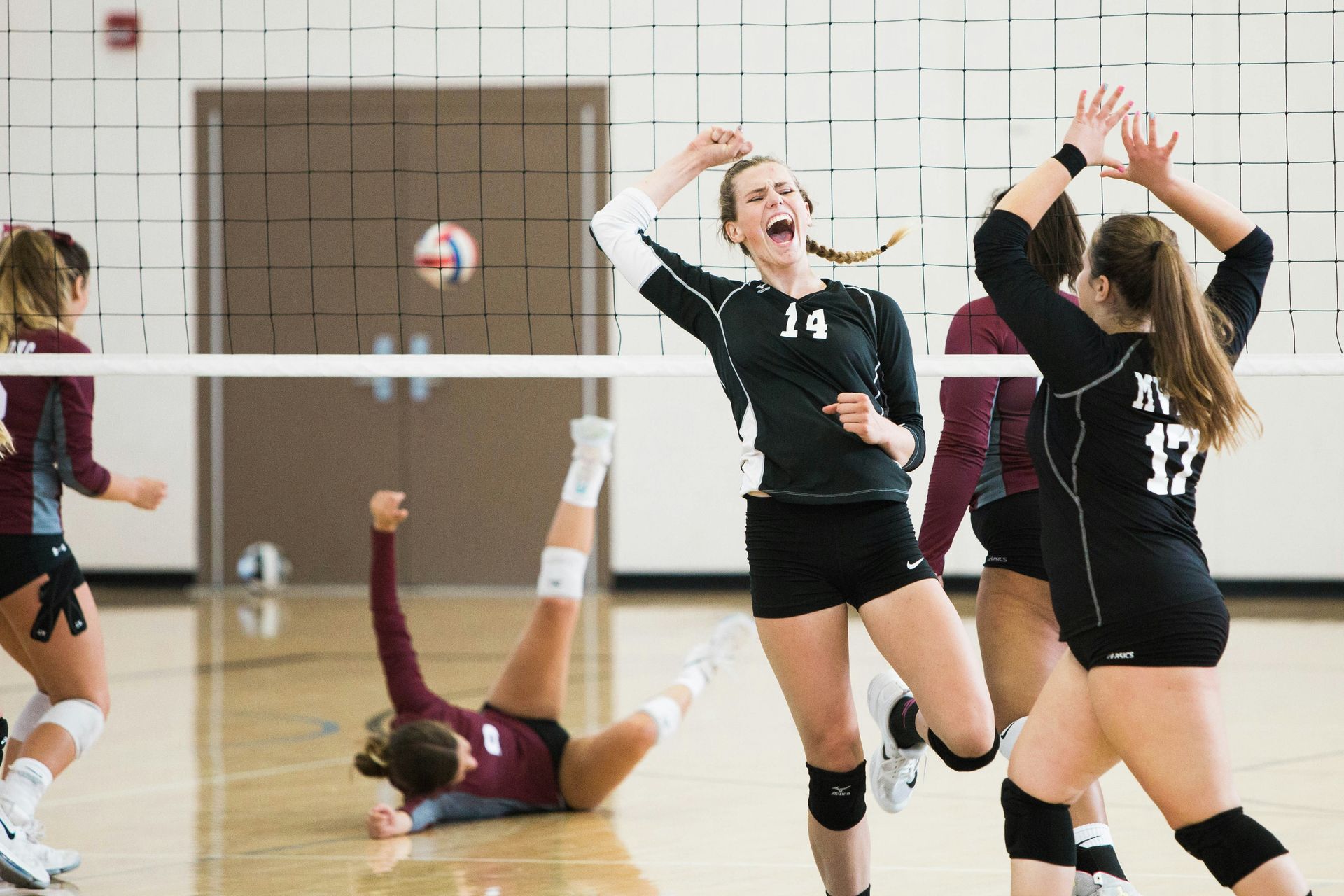 A group of women are playing volleyball in a gym.