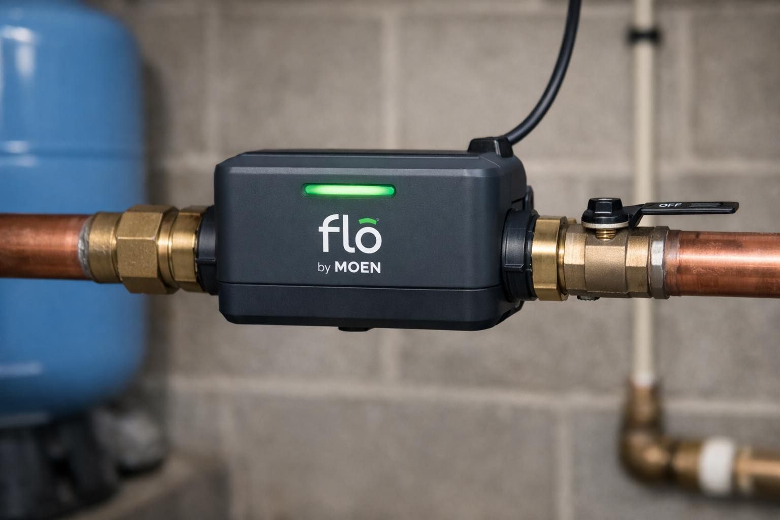 A Flo by Moen smart water monitor with a glowing green LED installed on a residential copper pipe system.