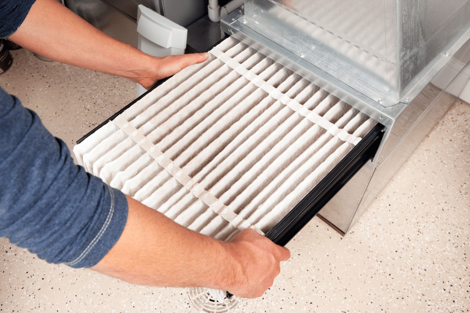 Hands sliding a white dishwasher rack into an open dishwasher interior.