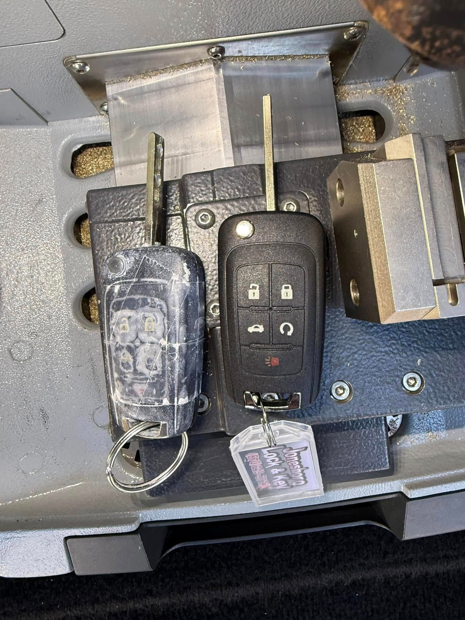 Two car keys are sitting on top of a metal surface.