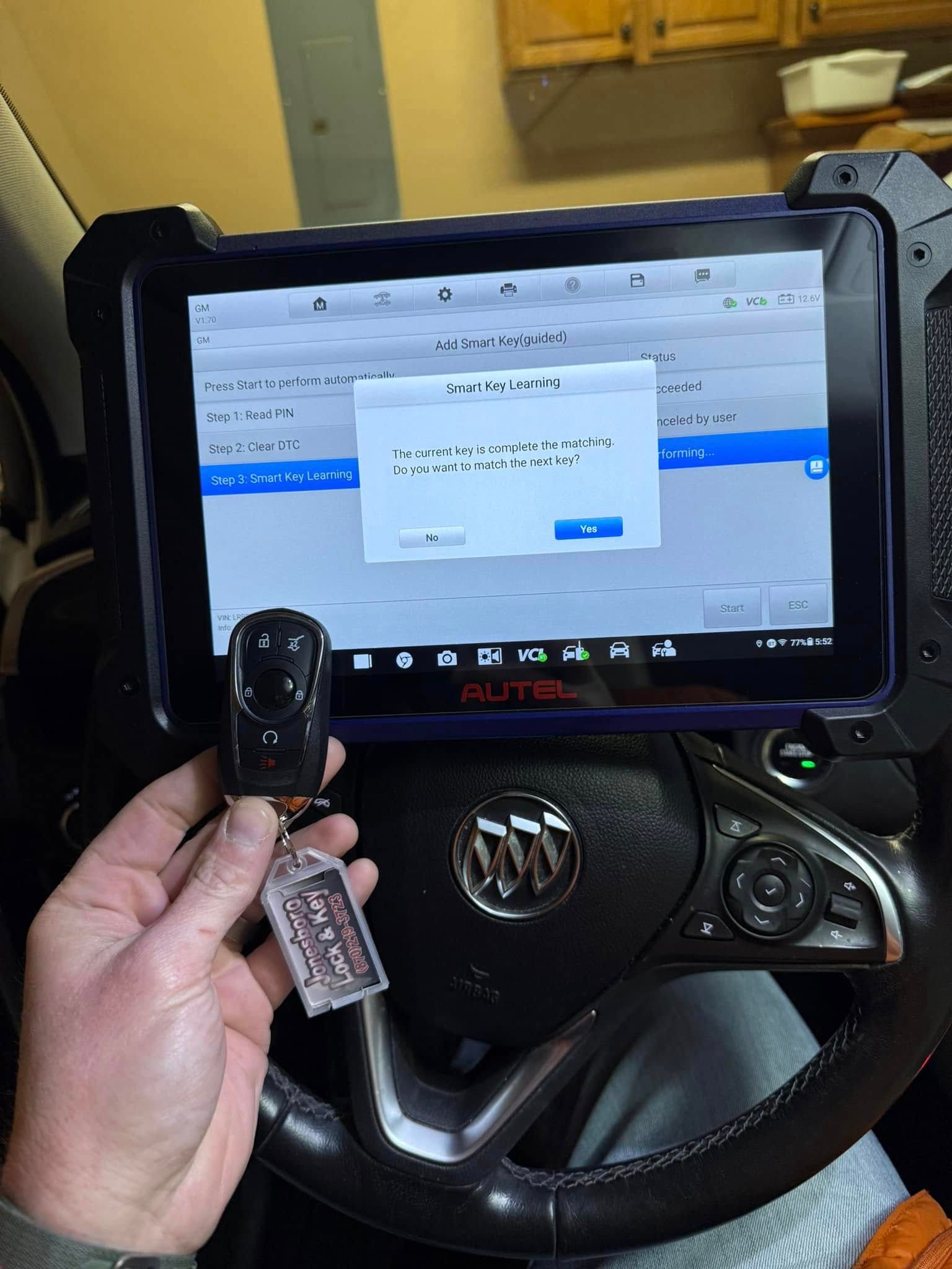 A person is holding a key in front of a tablet in a car.
