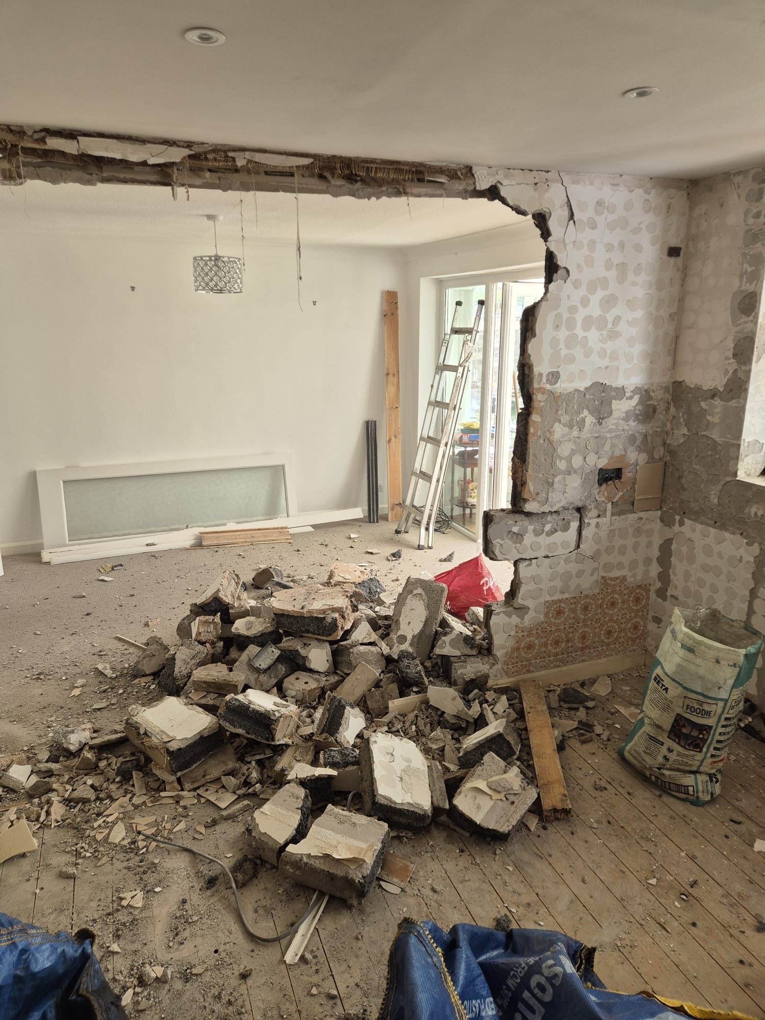 A room with a hole in the wall and a pile of bricks on the floor.