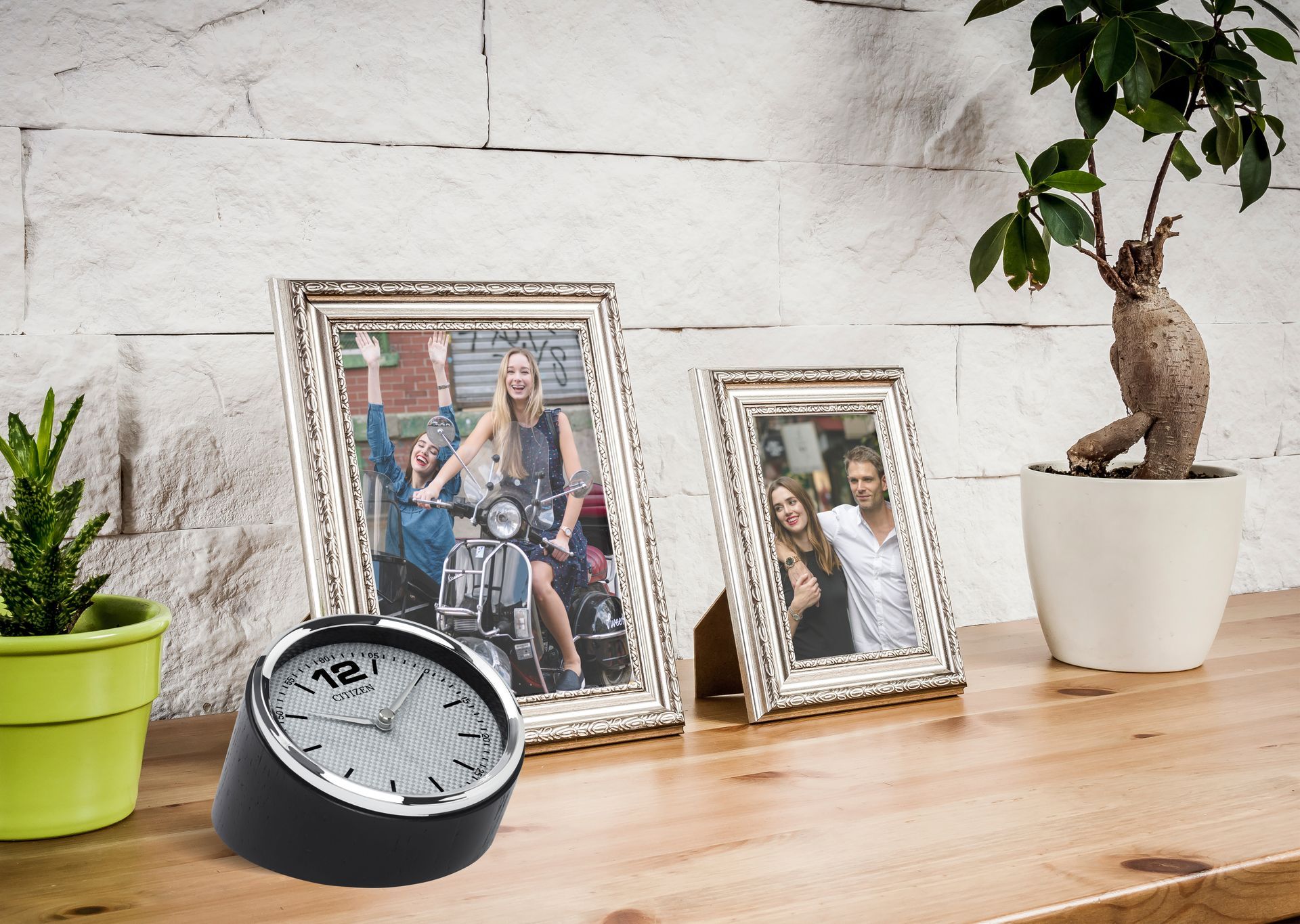 Two picture frames and a clock on a wooden table
