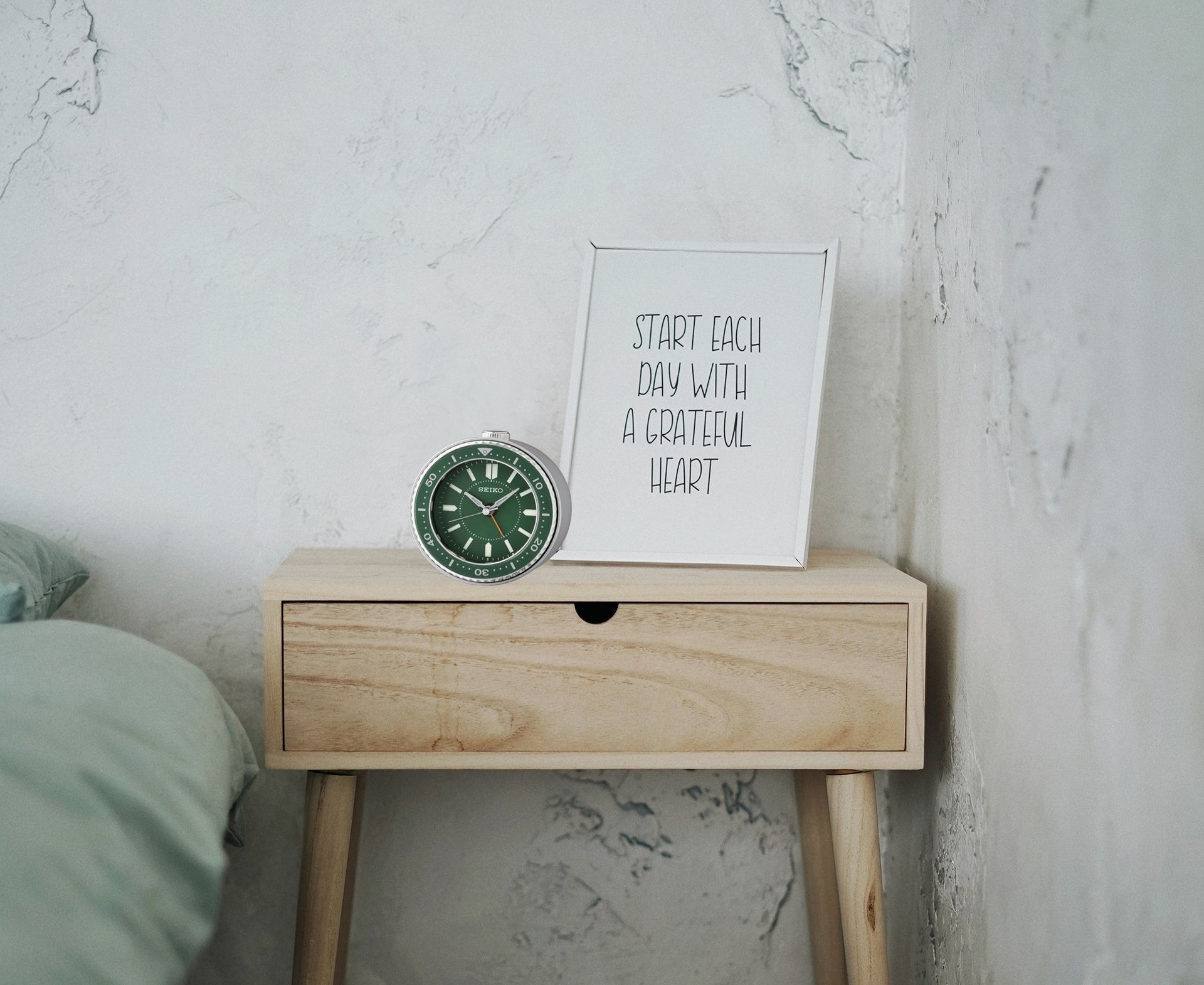 A nightstand with a clock and a sign on it