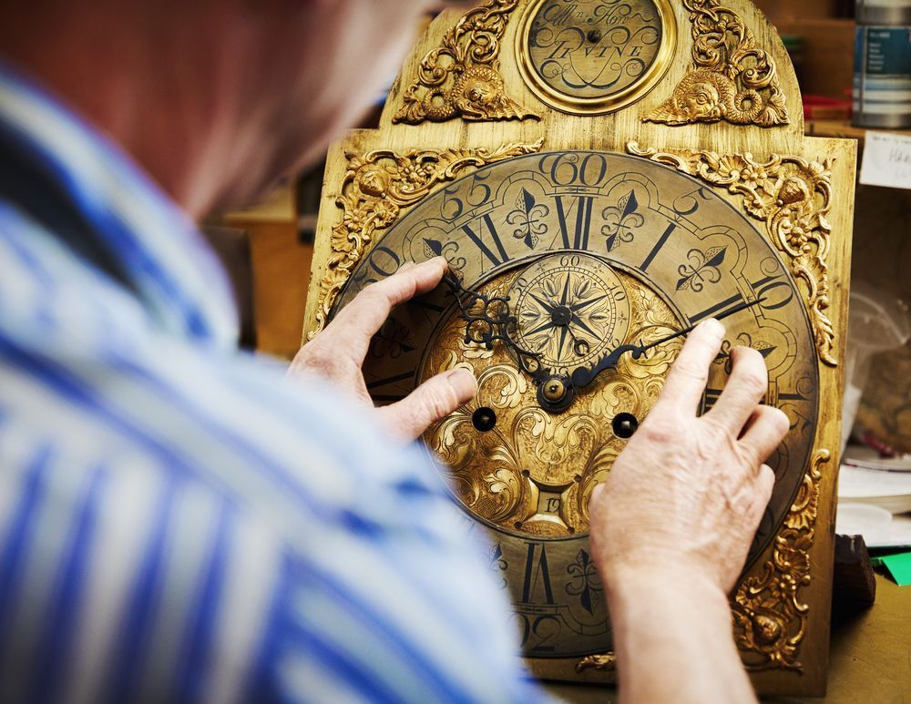 A clock maker moving the hands on an antique clock