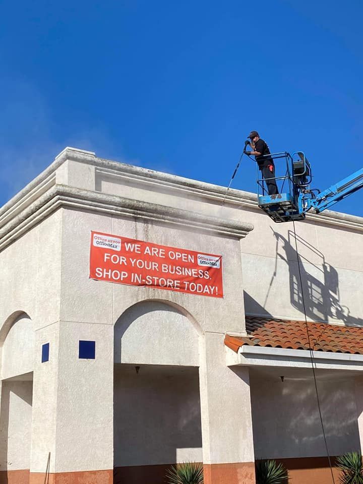 A man is cleaning the side of a building with a crane.