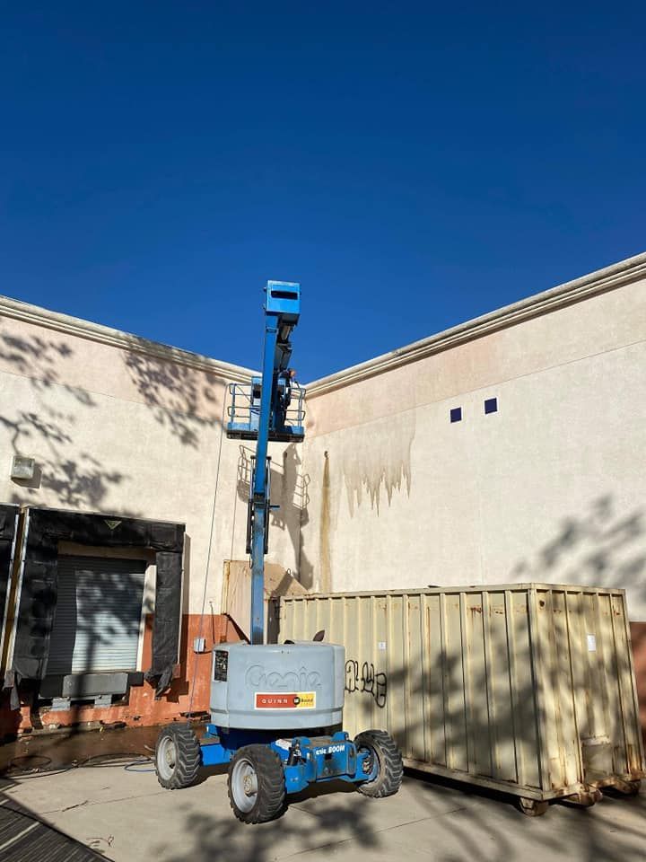 A blue aerial lift is parked in front of a building.