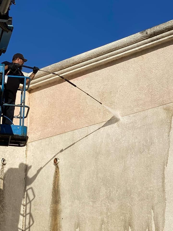 A man is cleaning a building with a high pressure washer.