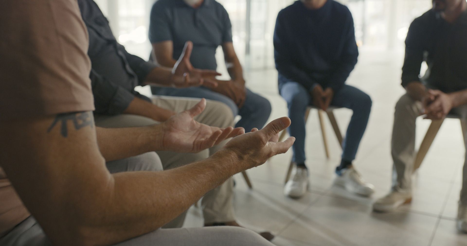 A group of men are sitting in a circle talking to each other