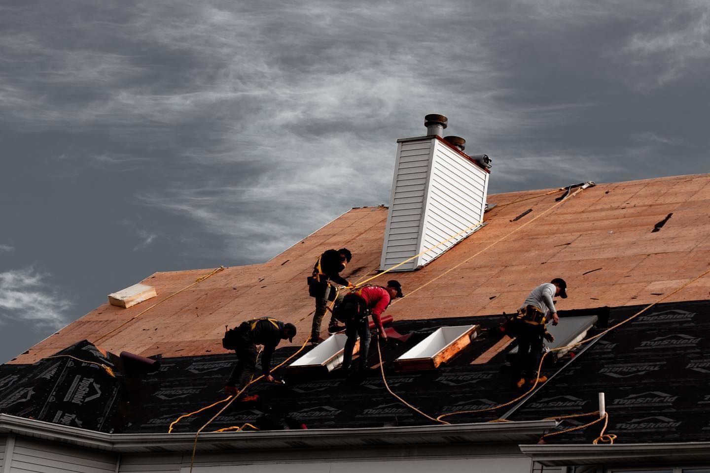 A group of men are working on the roof of a house.