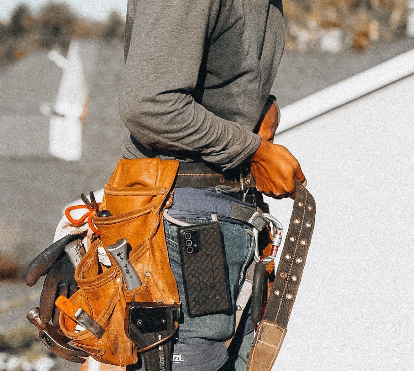 A man wearing a tool belt with a cell phone in it