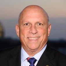 Bald man smiling, wearing a suit and tie.