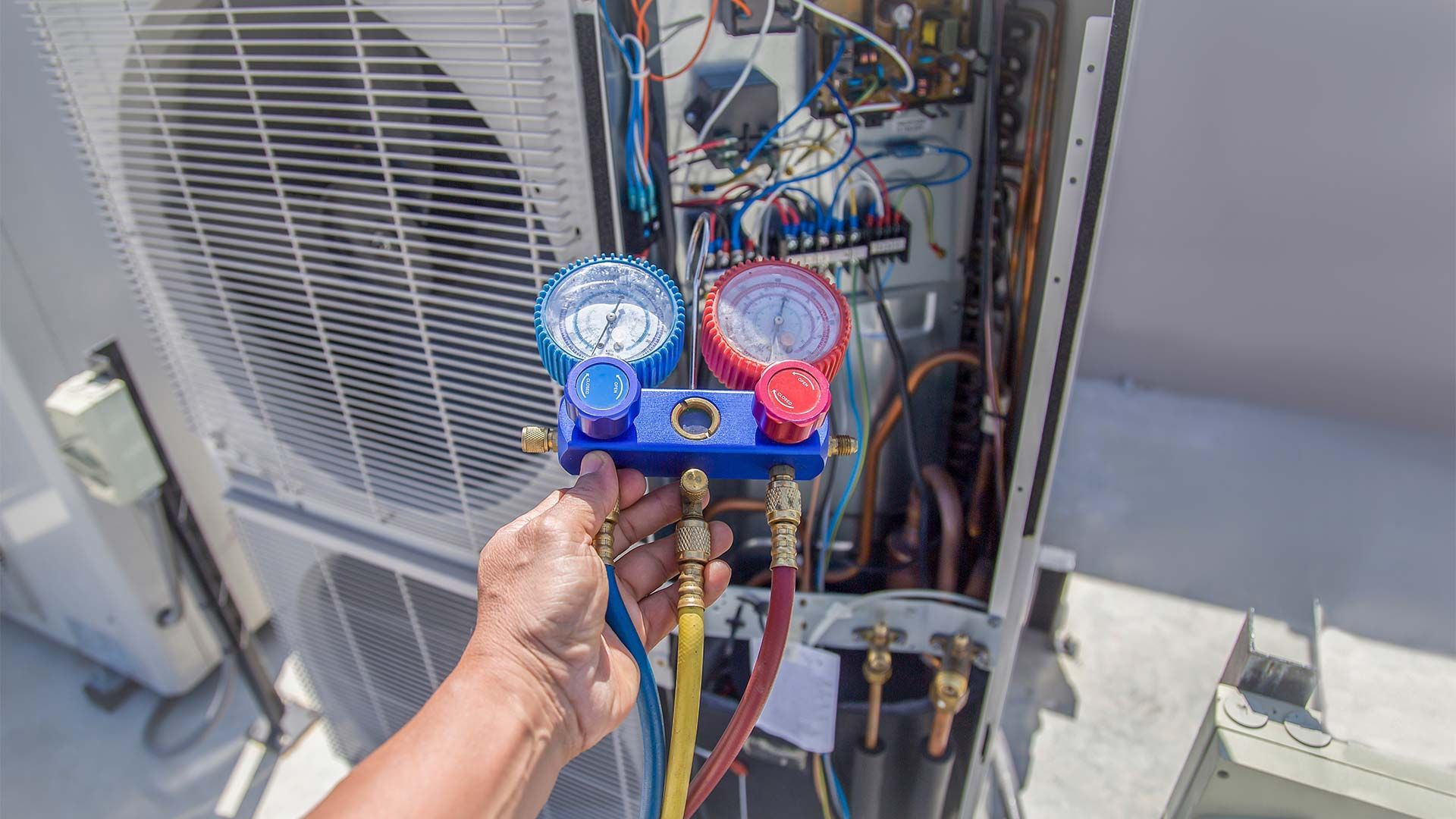 A person is working on an air conditioner with a gauge.