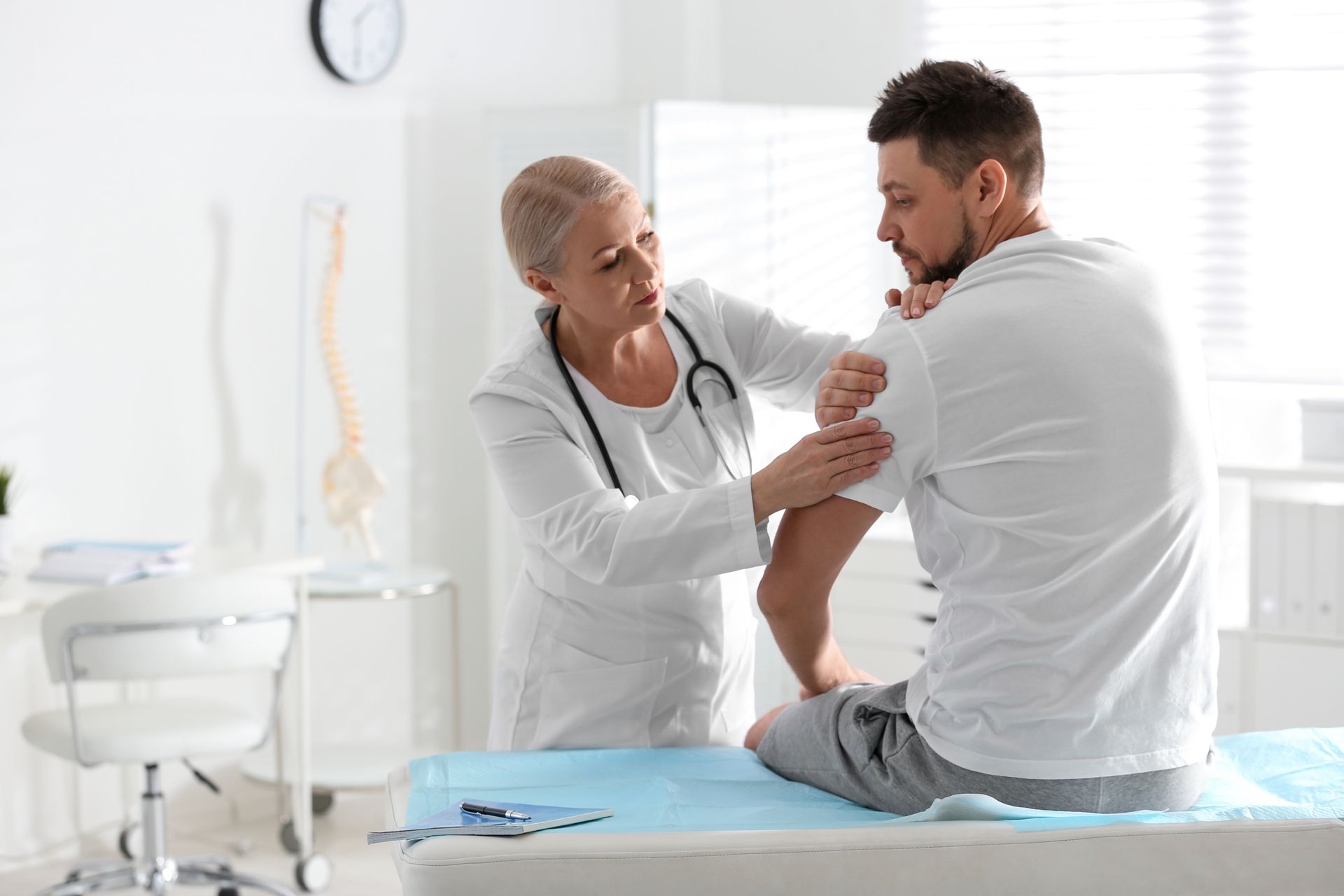 An orthopedist is examining a patient’s arm.