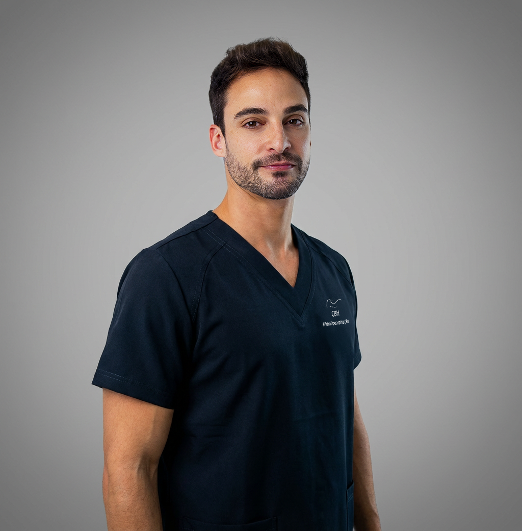 Um homem de camisa preta está de pé com os braços cruzados.