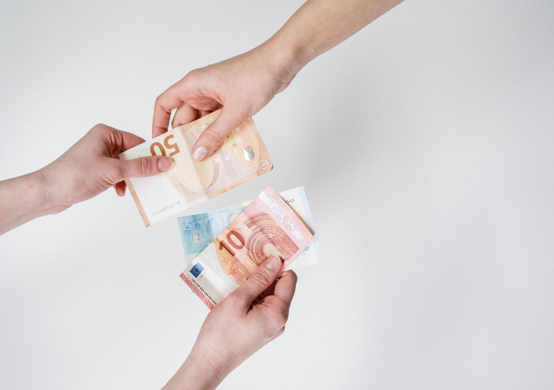 Mãos trocando cédulas de real, incluindo notas de 50, 10 simbolizando economia