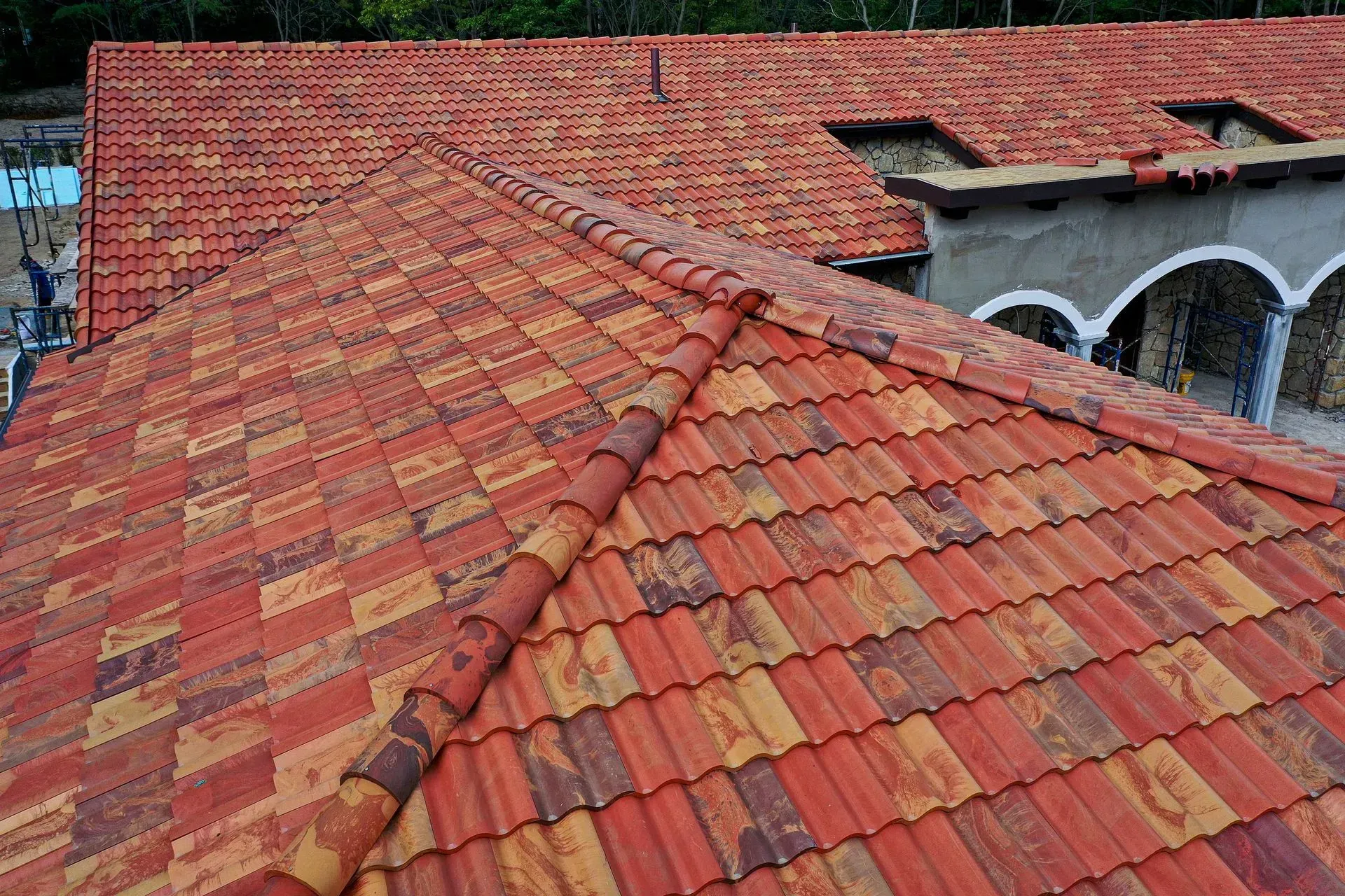 Red clay tile roof on a building. Tiles are multi-colored, with a ridge cap.