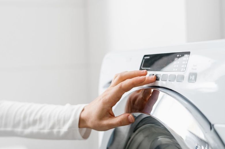 A person is pressing a button on a washing machine.
