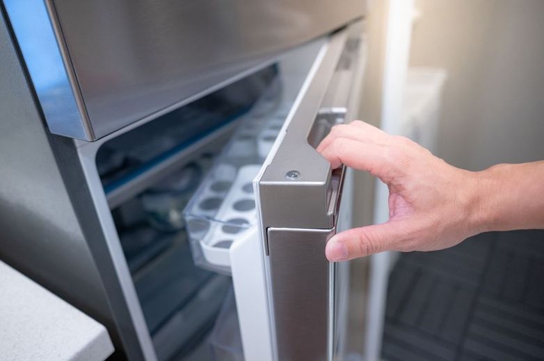 A person is opening the door of a refrigerator.