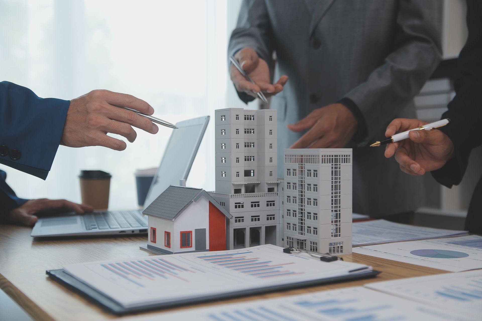 People discussing real estate plans with architectural models and documents on a table.