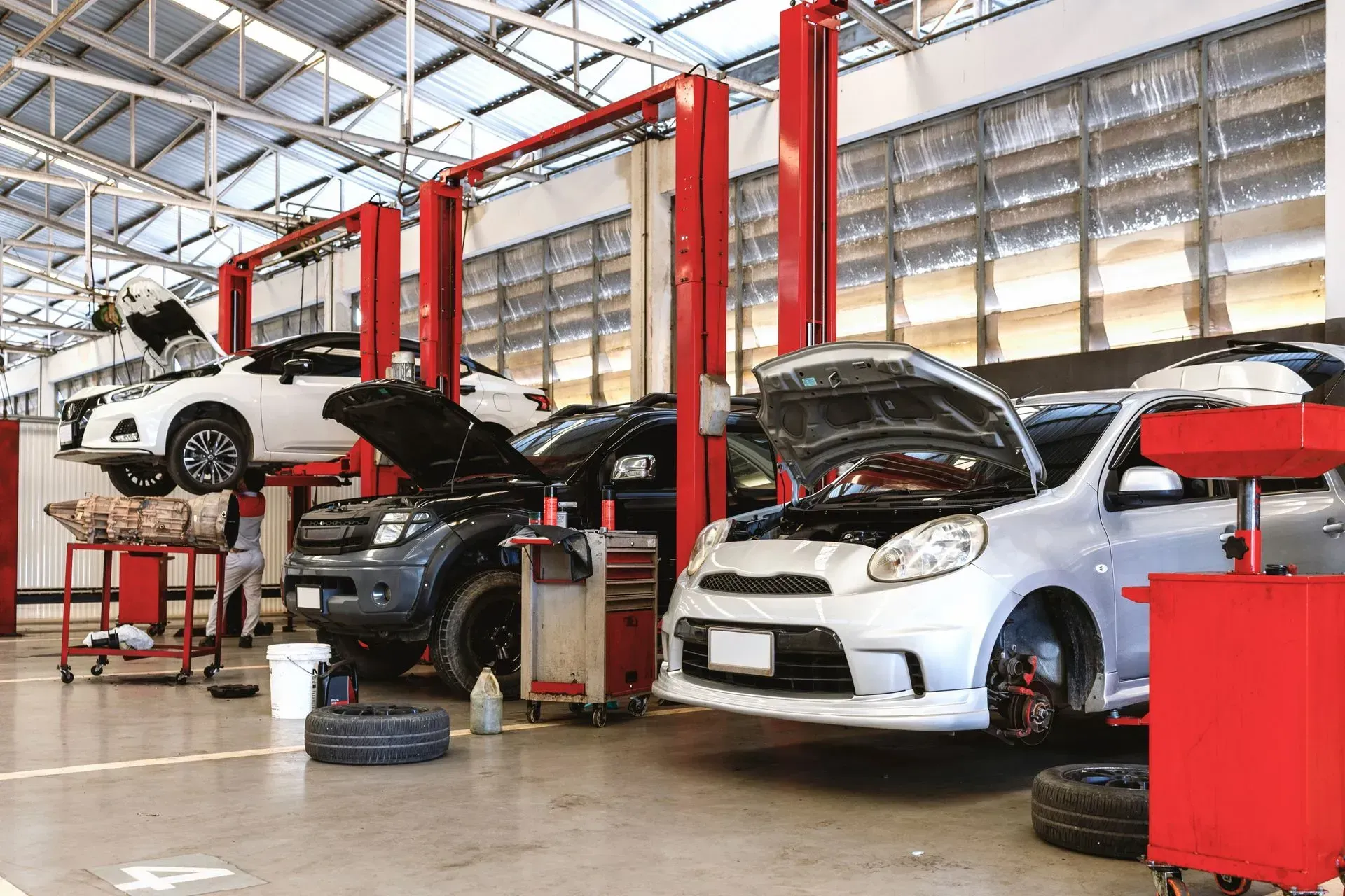 Auto repair shop with three cars on lifts and a mechanic working underneath one vehicle.