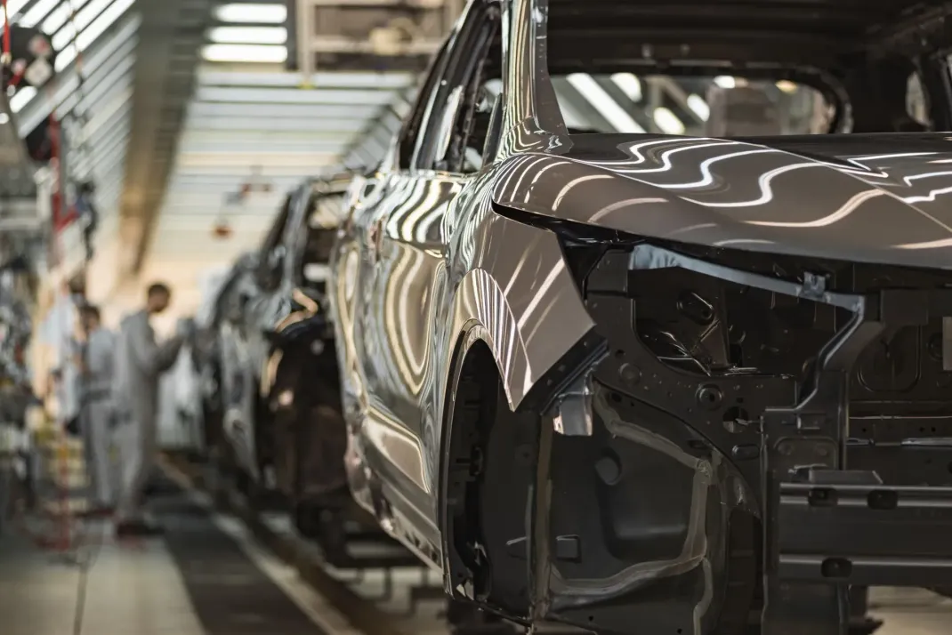 Car assembly line with a dark SUV body under production in a factory