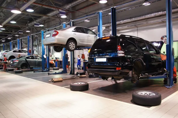 Auto repair shop with cars on lifts and mechanics working in a garage