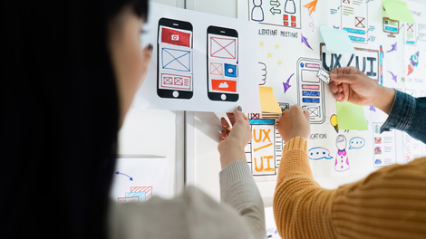 A group of people are working on a project on a whiteboard for mobile app development