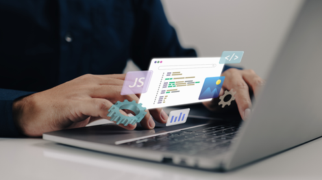 A man is typing on a laptop computer with web development code graphics hovering over the laptop