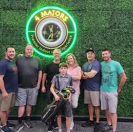 A group of people are posing for a picture in front of a sign that says 4 majors.