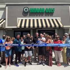 A group of people are standing in front of a building holding a blue ribbon.