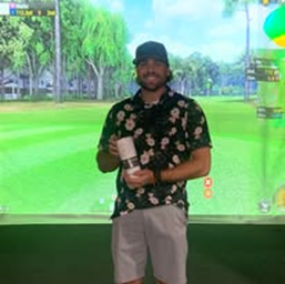 A man is standing in front of a screen holding a golf club.