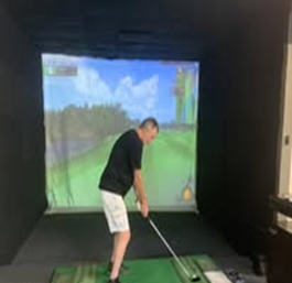 A man is playing a video game of golf in a simulator.