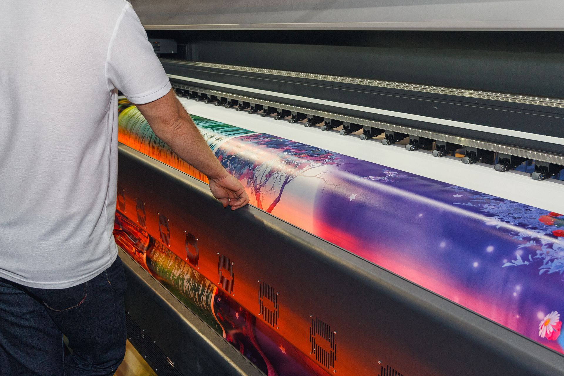 Worker operating large-format printer, producing vibrant banner or poster with high-quality design. Worker operating large-format printer, producing vibrant banner or poster with high-quality design.