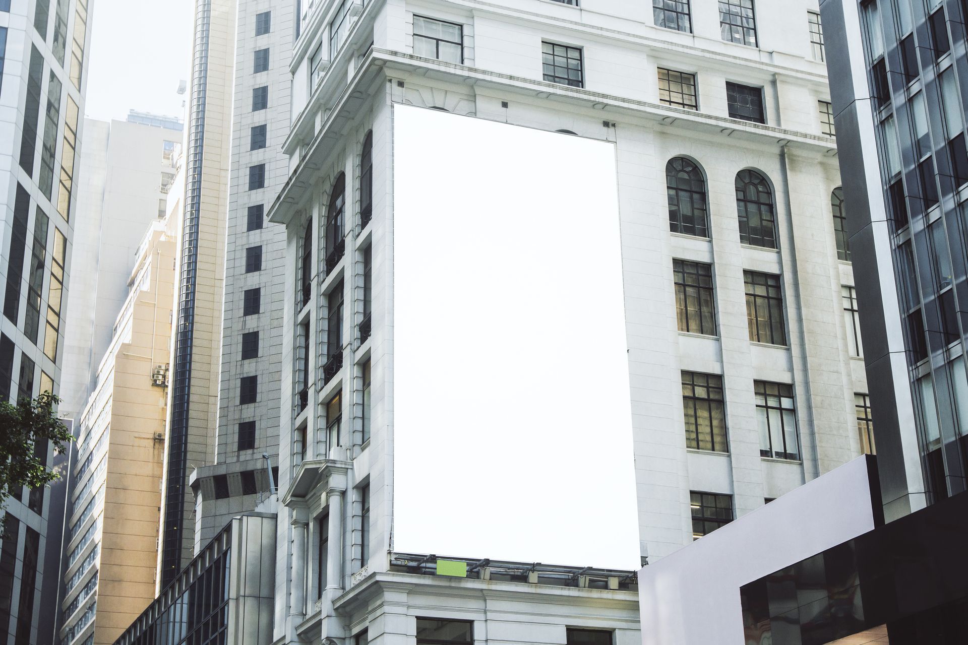 Large blank billboard mounted on a downtown building, surrounded by modern architecture.