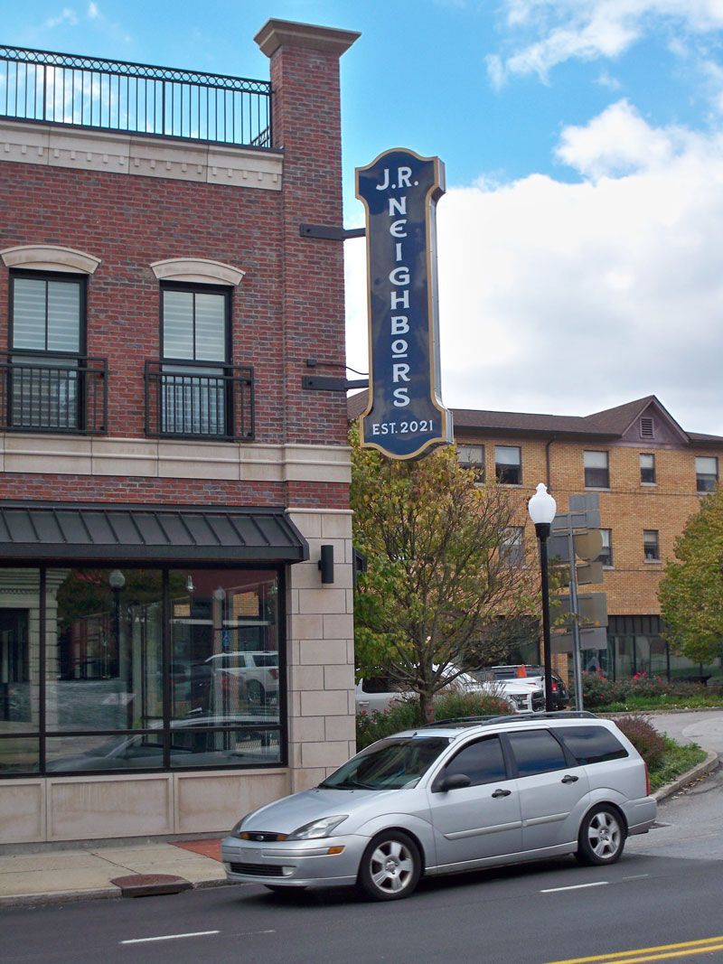 Exterior of J.R. Neighbors restaurant with sign, brick building, silver car parked in front.