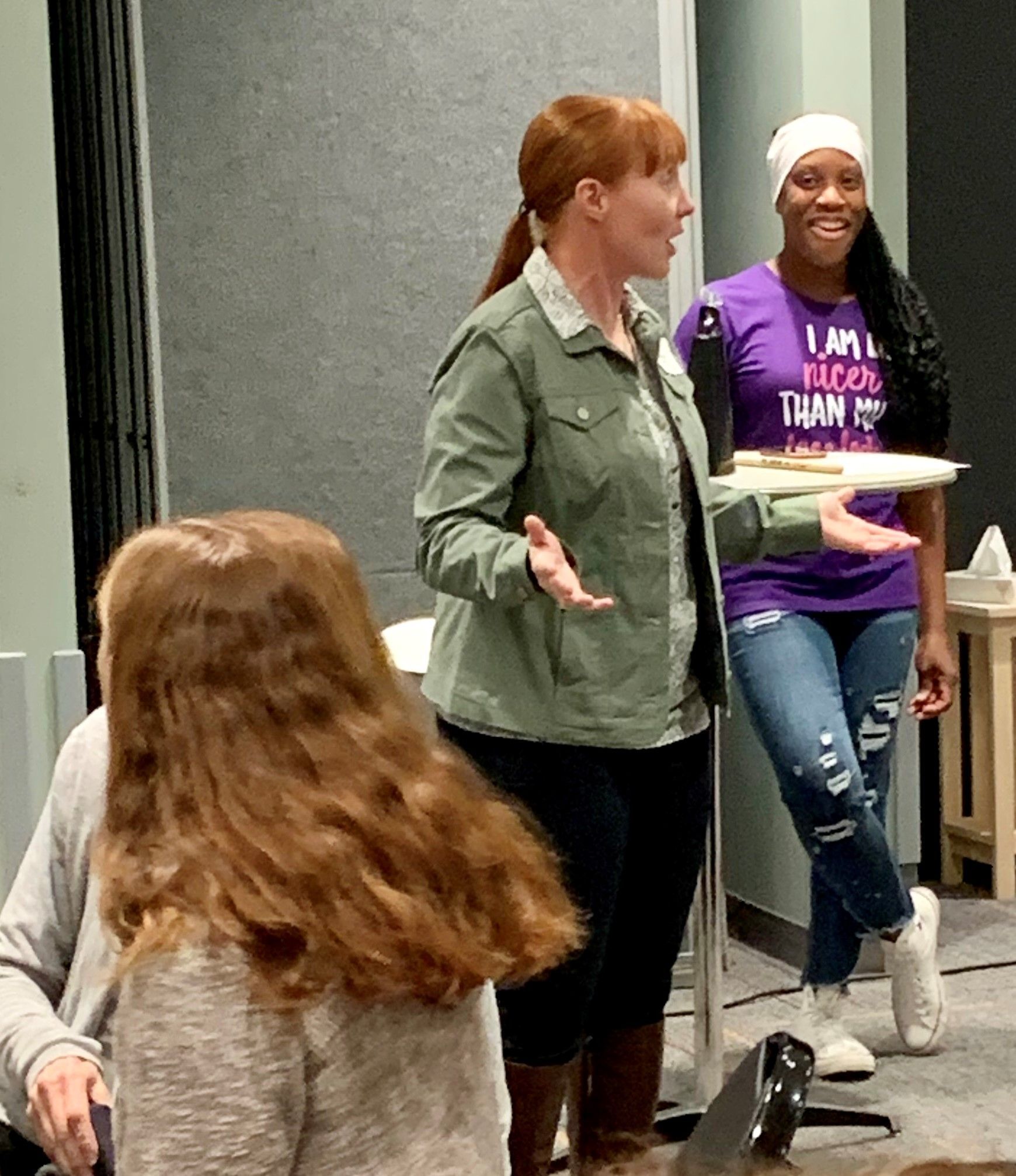 A woman in a purple shirt that says i am taco than you is standing next to a woman in a green jacket.