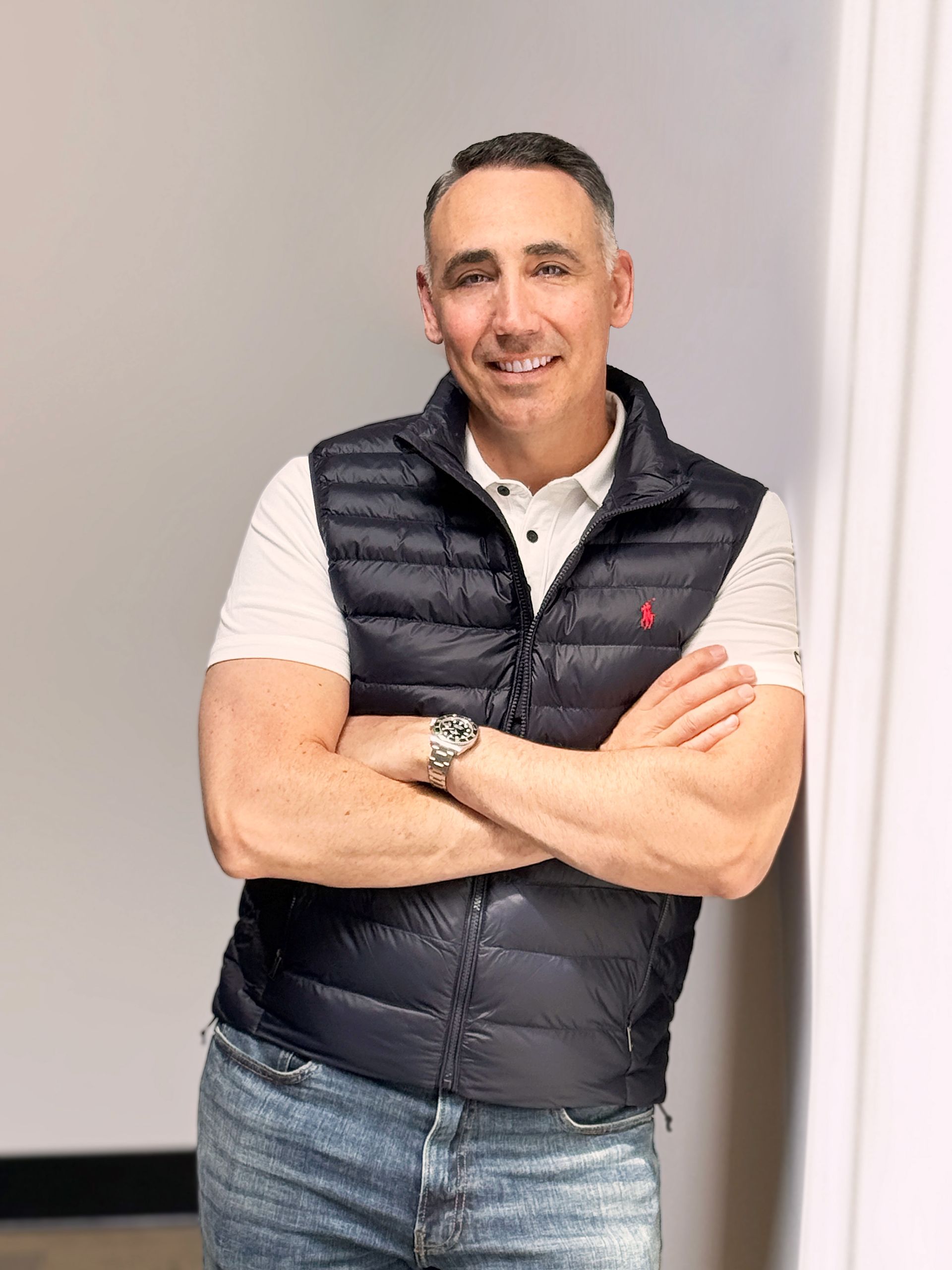 A man in a suit is leaning against a brick wall with his hands in his pockets.