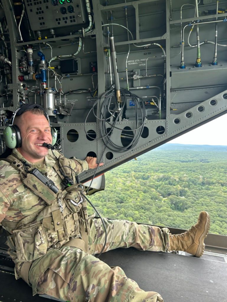 A man in a military uniform is sitting in the cockpit of a helicopter.