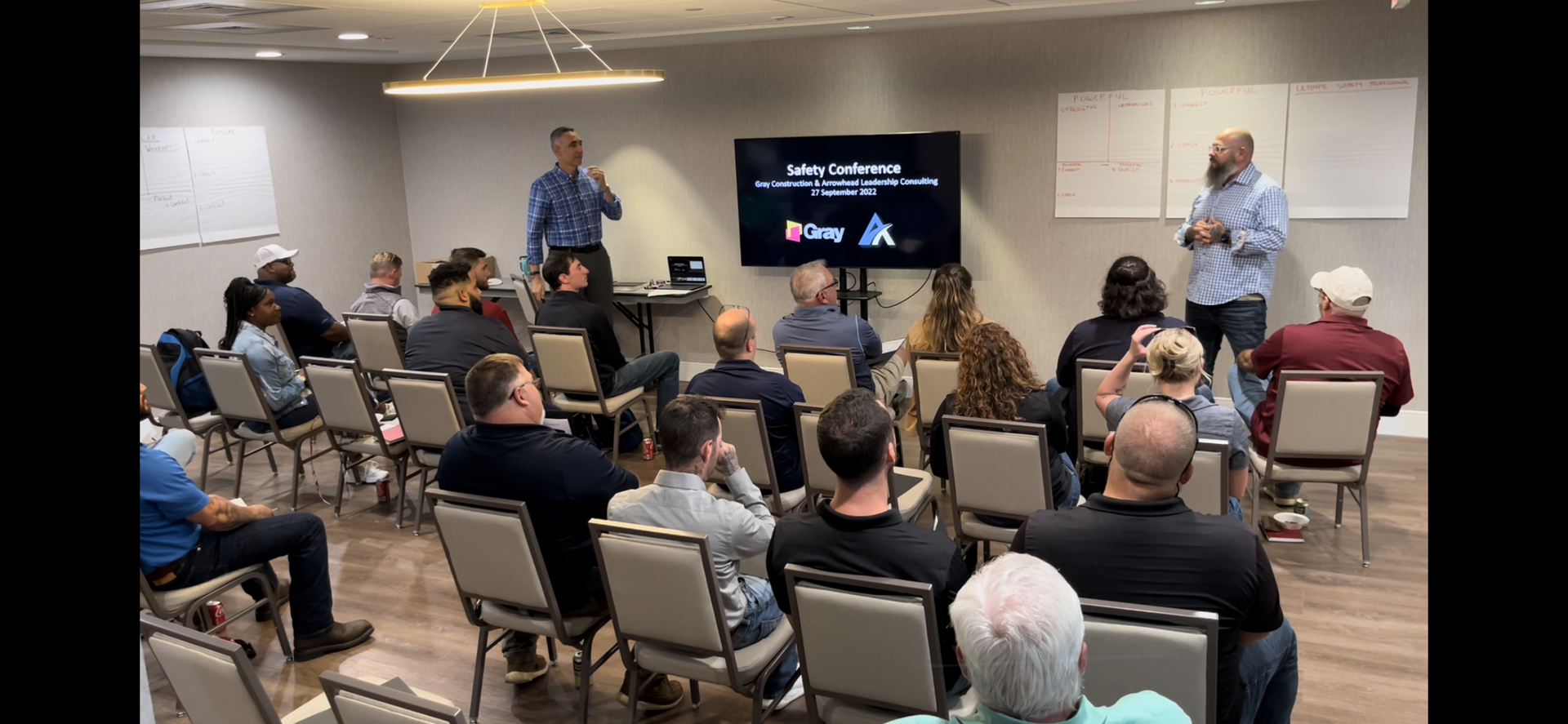 A group of people are sitting in chairs in a room watching a presentation.