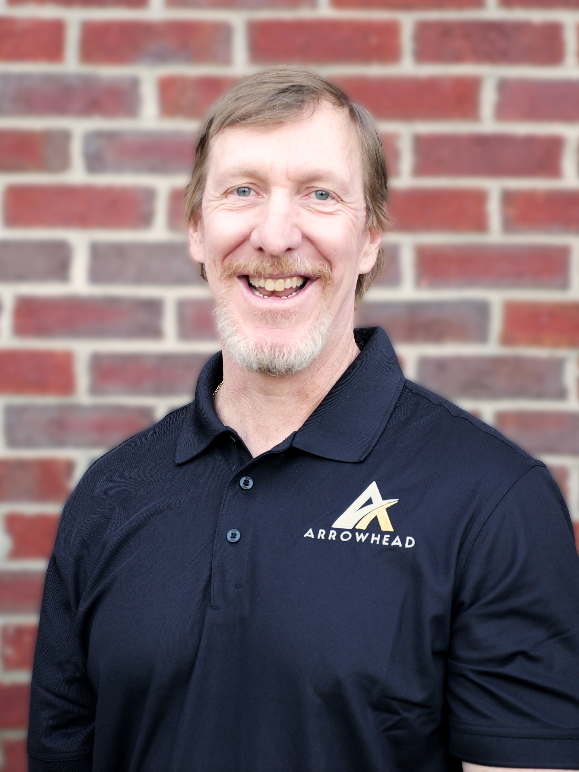 A man in a suit and blue shirt is smiling for the camera.