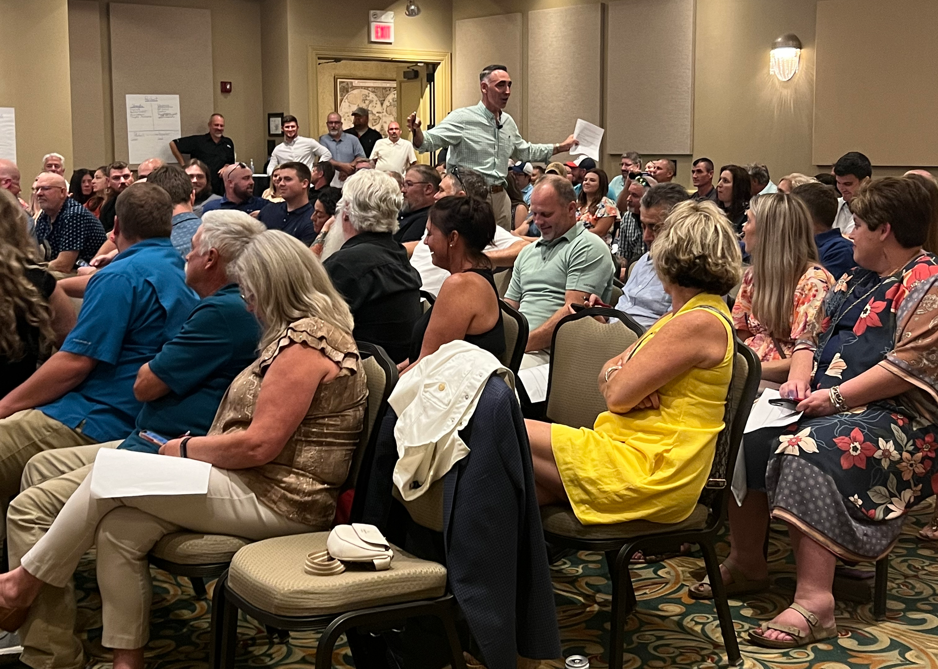 A large group of people are sitting in chairs in a room.
