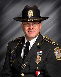 A man in a police uniform is wearing a hat and glasses.
